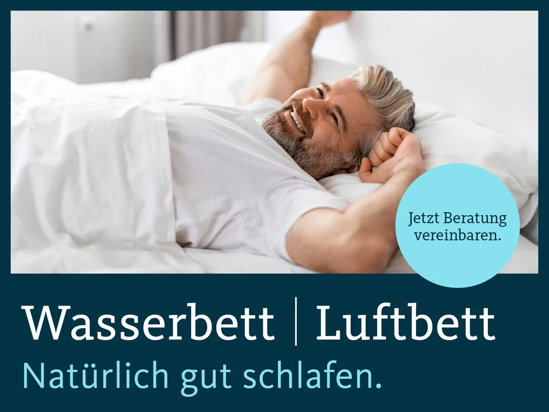Ein Mann in einem Bett, ist gerade aufgewacht und strahlt, weil er sichtlich eine gut geschlafen hat.