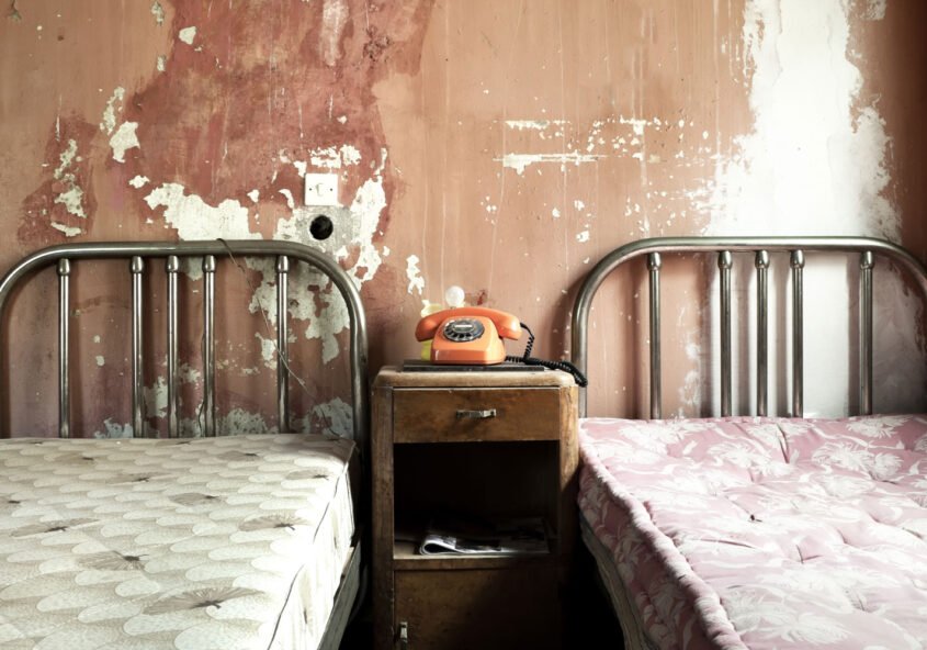 Zwei alte Betten in einem heruntergekommenen Zimmer.